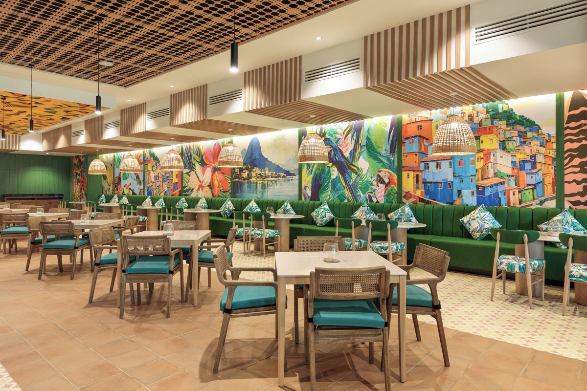 A restaurant with green cushioned seating, wooden tables, and a colorful mural on the wall.