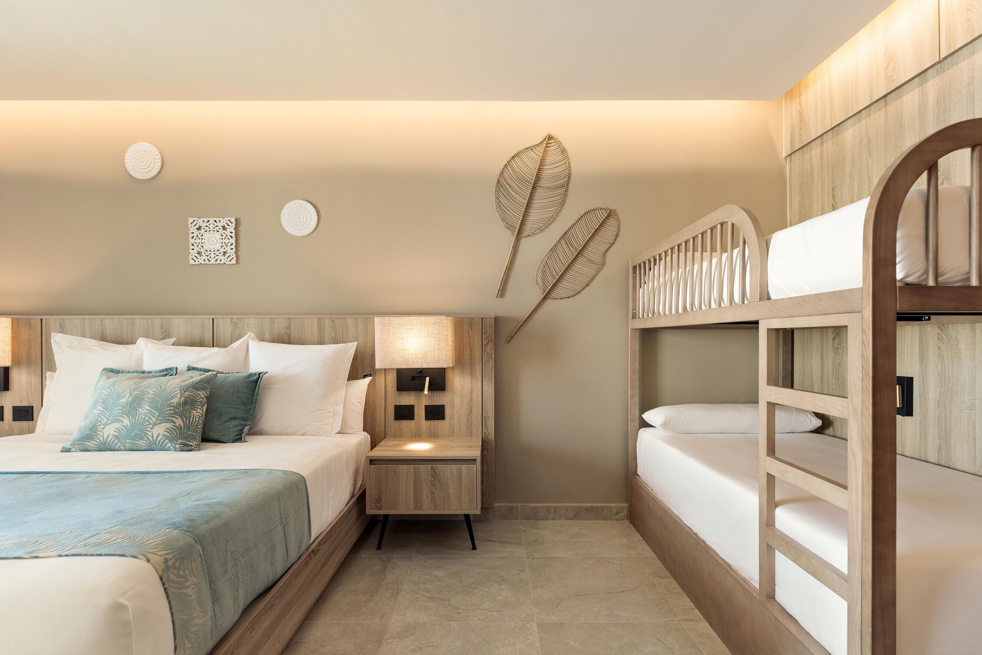 A hotel room with a bed, bedside tables, a nightstand, a lamp, and a bunk bed.