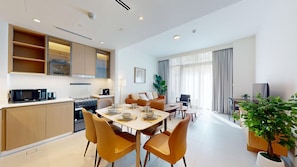 Eine moderne Wohnung mit Essbereich, Küche, Wohnzimmer und einem großen Fenster mit Vorhängen.