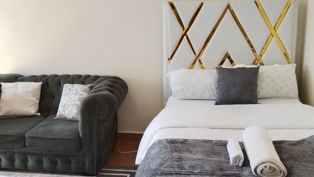 Quarto de hotel com cama, sofá, ventoinha no teto e tapete.
