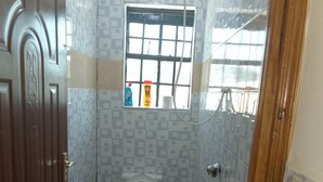 Uma casa de banho pequena com sanita, janela e chuveiro.