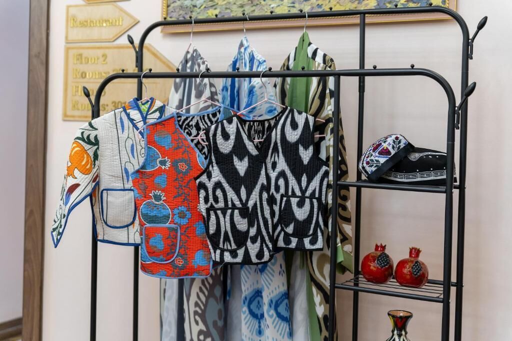 A rack with various patterned fabrics and a pomegranate-shaped vase.