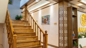 A wooden staircase with a decorative railing, a wall with a geometric pattern, and a shelf with decorative items. - ECO ART Hotel (Tashkent)