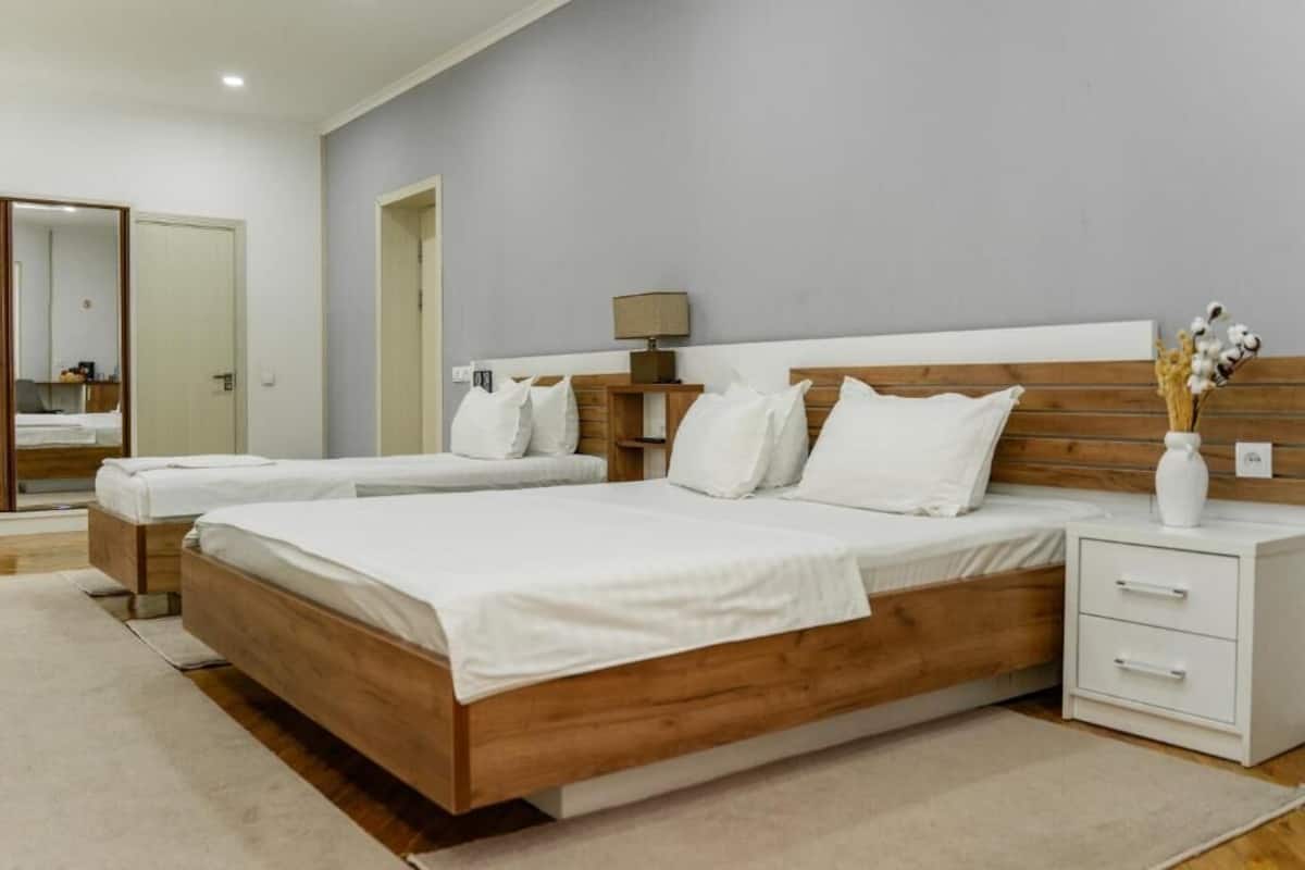 A bedroom with a large bed, two bedside tables, a nightstand, and a mirror.