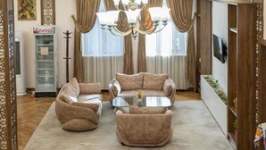 A living room with a sofa set, a glass coffee table, and a chandelier. - ECO ART Hotel (Tashkent)