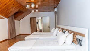 A bedroom with two beds, wooden ceiling beams, and a white wall. - ECO ART Hotel (Tashkent)