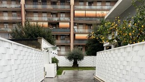 A courtyard with a tiled floor, white brick walls, and a tree in the center. - GREY HOUSE SRLS (Latina)