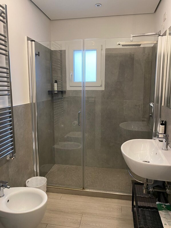 A modern bathroom with a glass-enclosed shower, two sinks, and a bidet. - GREY HOUSE SRLS (Latina)