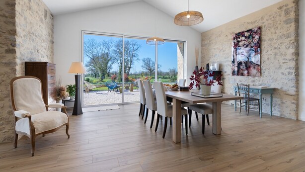 A dining area with a wooden table, chairs, a lamp, and a painting on the wall.