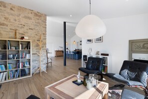 Un soggiorno moderno con una libreria, due poltrone in pelle, un tavolino in legno e un lampadario.