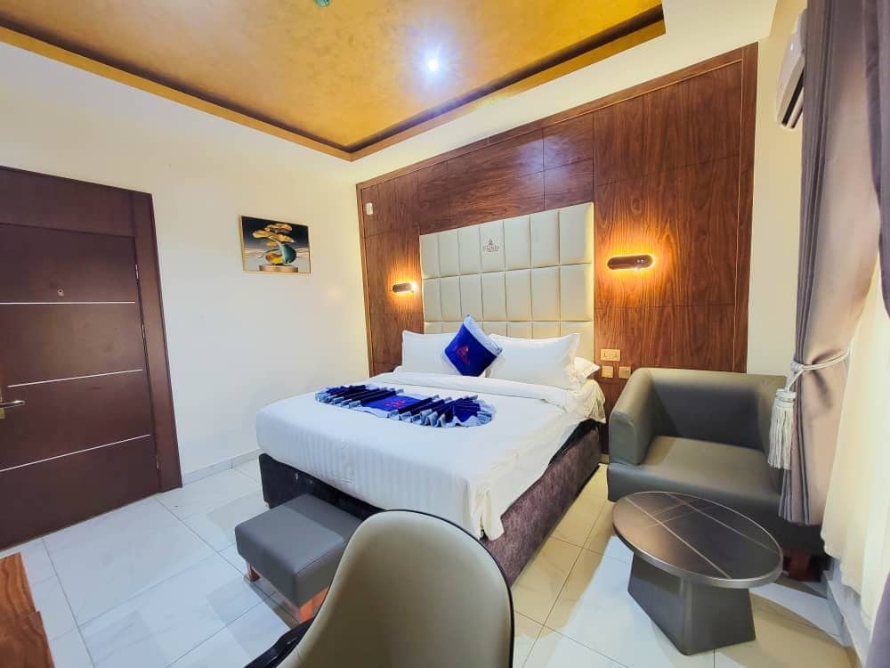 A hotel room with a bed, a desk, a chair, and a small table.