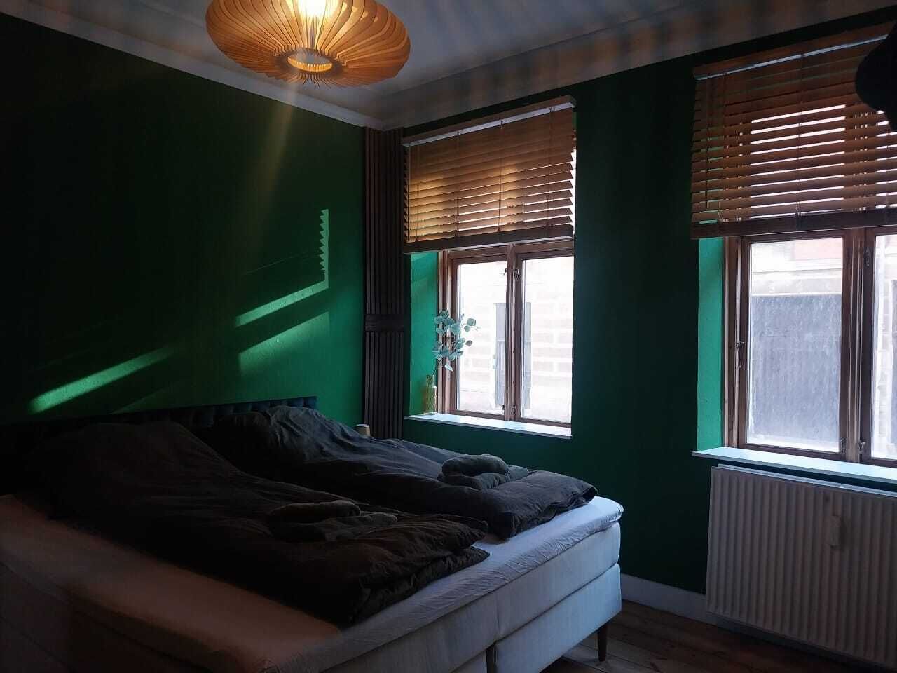 Un dormitorio con cama, ventana con persianas y radiador.