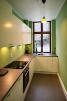 Una cocina con armarios blancos, una estufa negra y una ventana con vistas a árboles.
