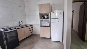 A compact kitchen with a stove, microwave, and refrigerator. - Prehenn Beach House with Pool (Itapoá)