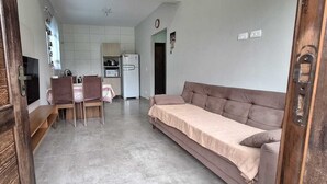 A compact living space with a kitchenette, a dining area, and a sofa. - Prehenn Beach House with Pool (Itapoá)