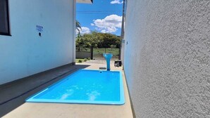 A small, rectangular pool with a blue interior, surrounded by a concrete deck. - Prehenn Beach House with Pool (Itapoá)