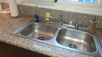 A kitchen with a double stainless steel sink, a window above the sink, and a granite countertop.