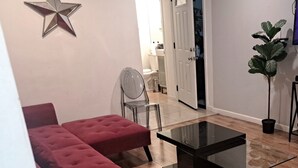 Ein Wohnzimmer mit einem roten Sofa, einem Glastisch und einer Sternen-Dekoration an der Wand.