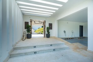 Un interior modern amb una escala que condueix a una porta, plantes en testos i un disseny net i minimalista.