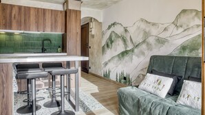 Una cocina moderna con armarios de madera, una zona con taburetes de bar y un mural de montañas en la pared.