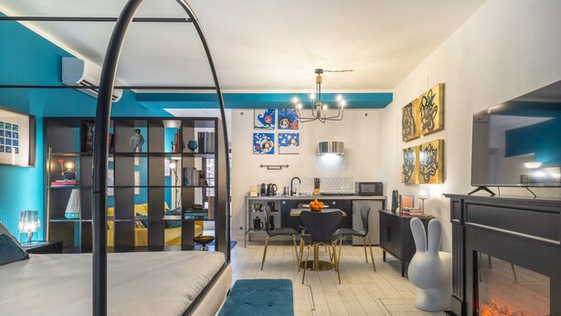 A modern bedroom with a four-poster bed, a small kitchenette, and a living area with a fireplace. - Ca' Petunia Art Apartment R&R (Venecia)
