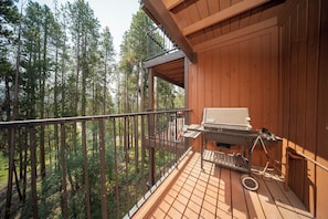 A wooden deck with a grill and a metal railing overlooking a forest. - Warm, Inviting & newly renovated condo with solid wood furnishings and updated t (Winter Park)