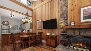 Un interior de madera con comedor, cocina y chimenea.
