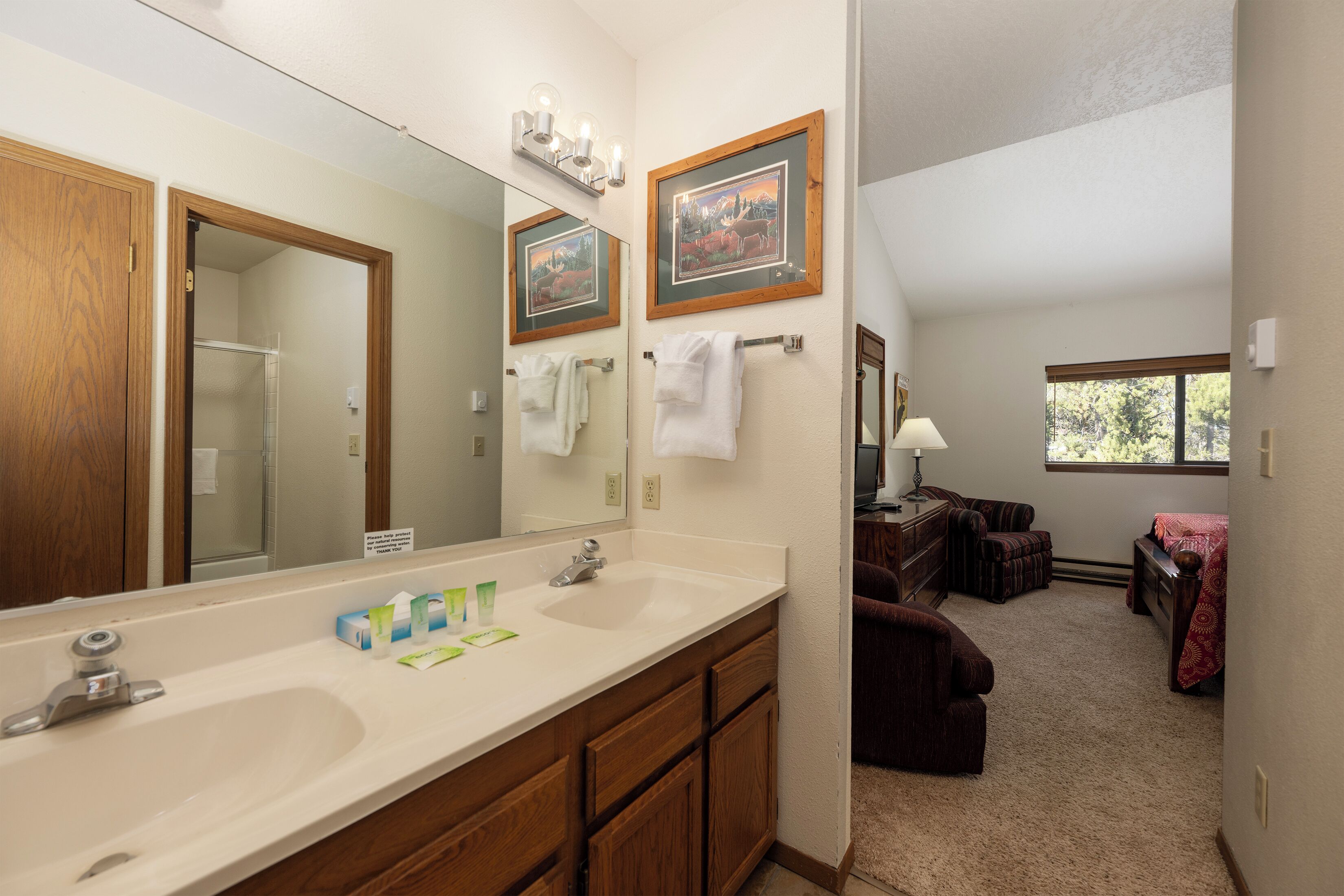 A bathroom with a large mirror, wooden cabinets, a sink, and a towel rack.