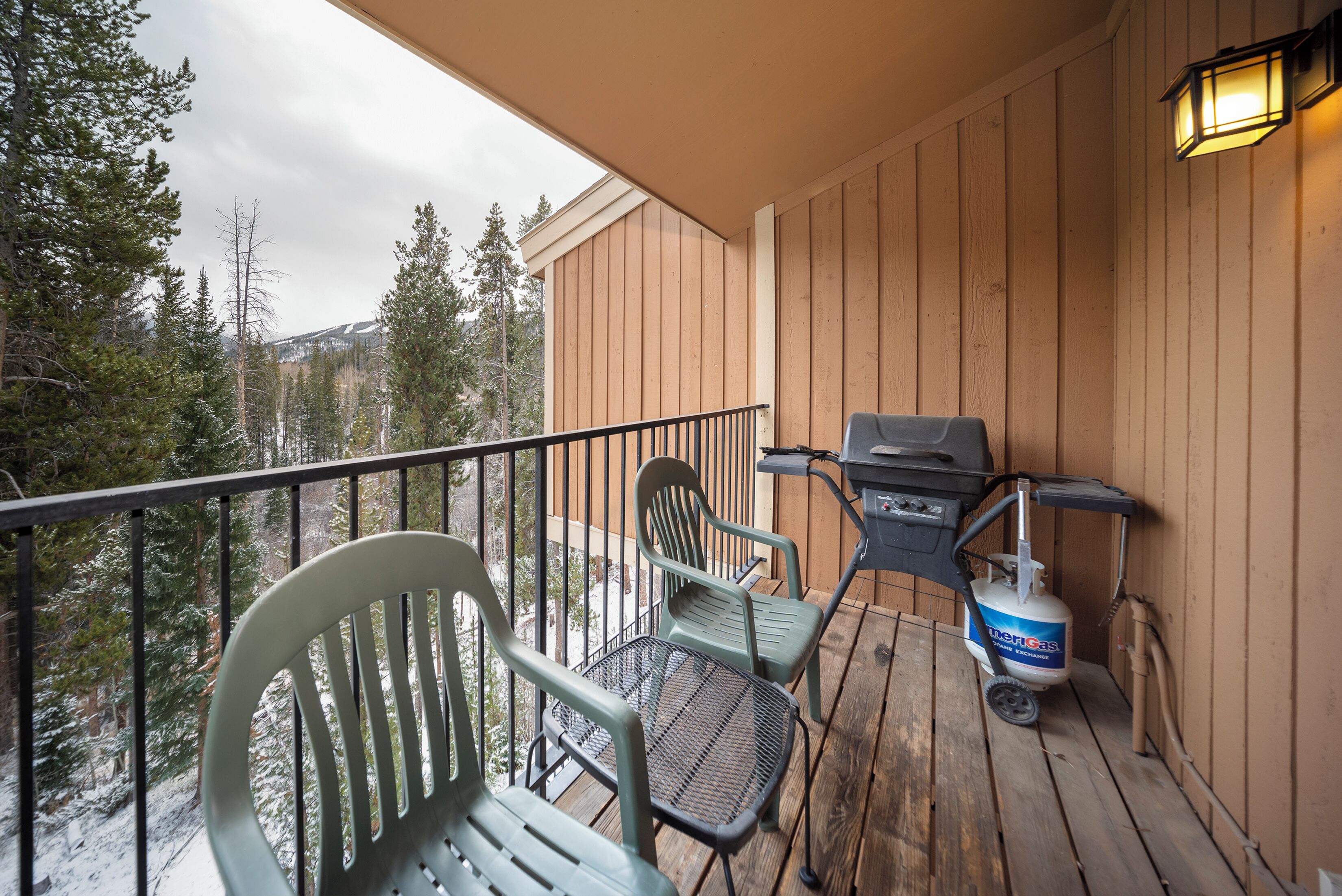 A wooden deck with outdoor furniture, a grill, and a propane tank.