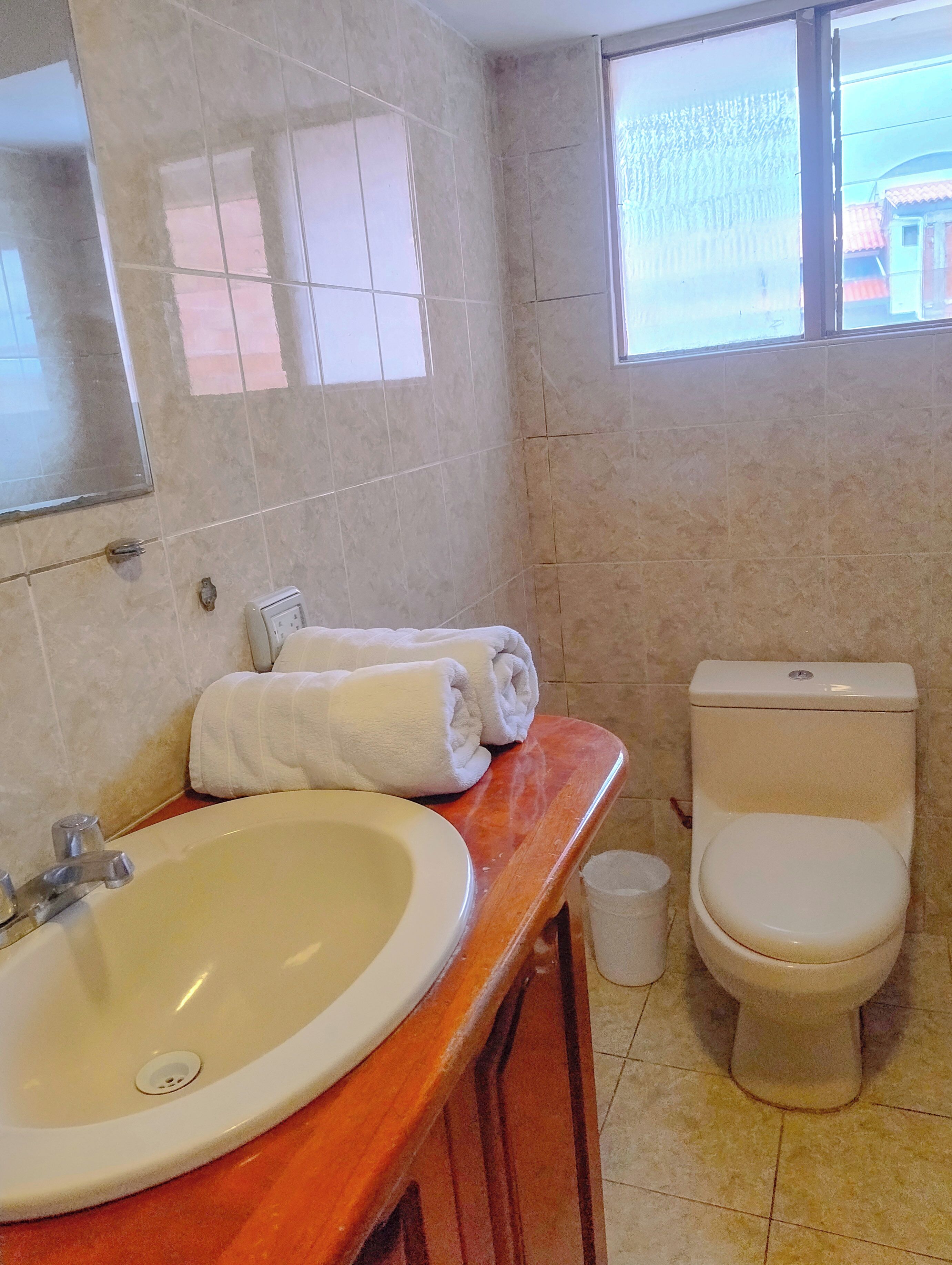 Un baño con lavamanos, inodoro y ventana.