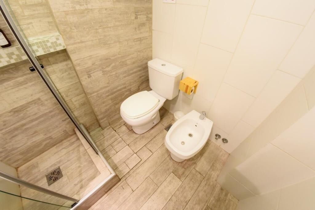 Une salle de bain comprenant des toilettes, un bidet et un espace douche.
