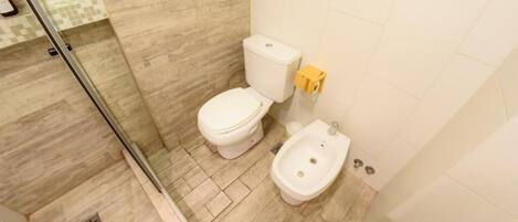 Une salle de bain comprenant des toilettes, un bidet et un espace douche.