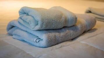 A neatly made bed with folded white towels and a wooden headboard.