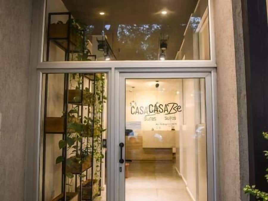 Ingresso di un hotel con porta in vetro, una scala interna e un cartello con la scritta 'CASA CASA Be Suites'.
