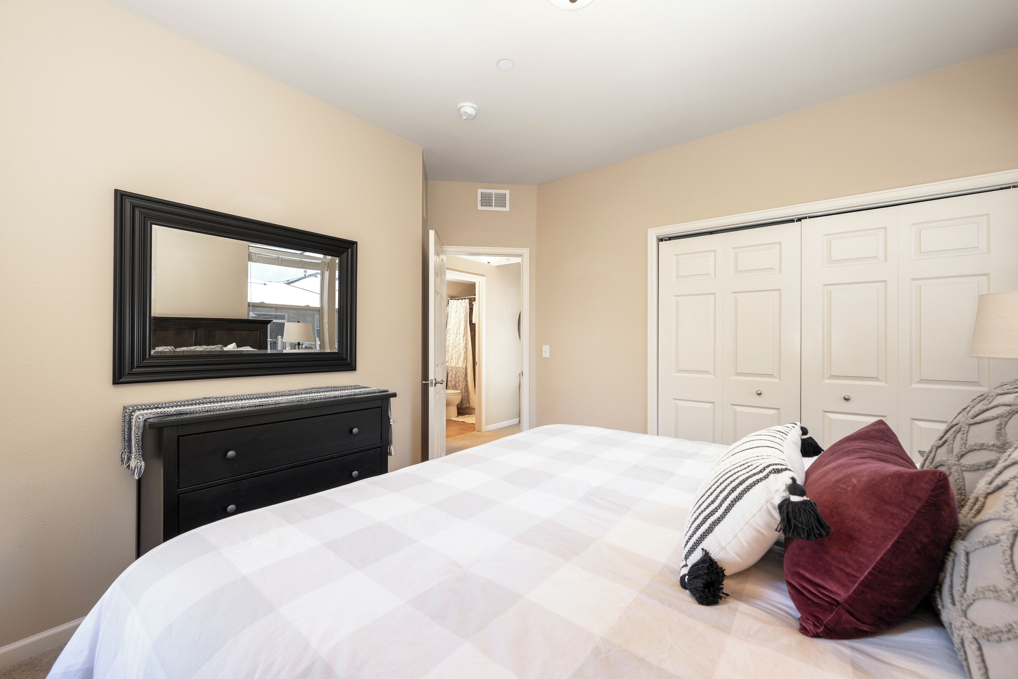 Une chambre à coucher avec un lit, une commode, un miroir et un placard.