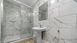 Un bany amb plat de dutxa de vidre, un lavabo i un mirall.