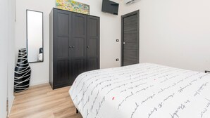 Ein Schlafzimmer mit Bett, Kleiderschrank, Fernseher und Kunstwerk an der Wand.