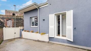 Un edificio moderno con fachada gris, contraventanas blancas y entrada protegida por una reja.