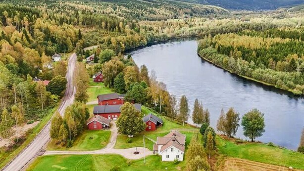 A rural landscape with a river, houses, and a road.