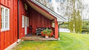 A red wooden building with a porch, a small table, and a chair.