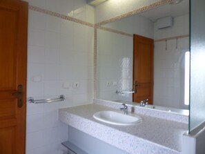 Casa de banho com lavatório branco, espelho e porta-toalhas.