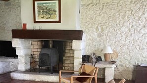 A rustic living room with a stone fireplace, wooden furniture, and a stone wall. - Mas du Coustoubi between Avignon and St Remy. Swimming pool, Pétanque, BBQ (Châteaurenard)