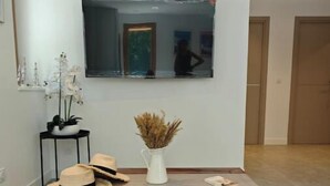 Ein Wohnzimmer mit einer Couch, einem Couchtisch, einem Spiegel und dekorativen Elementen, darunter eine Vase und Hüte.