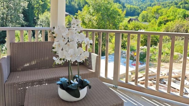 Ein Balkon mit Korbmöbeln und einem weißen Blumentopf.