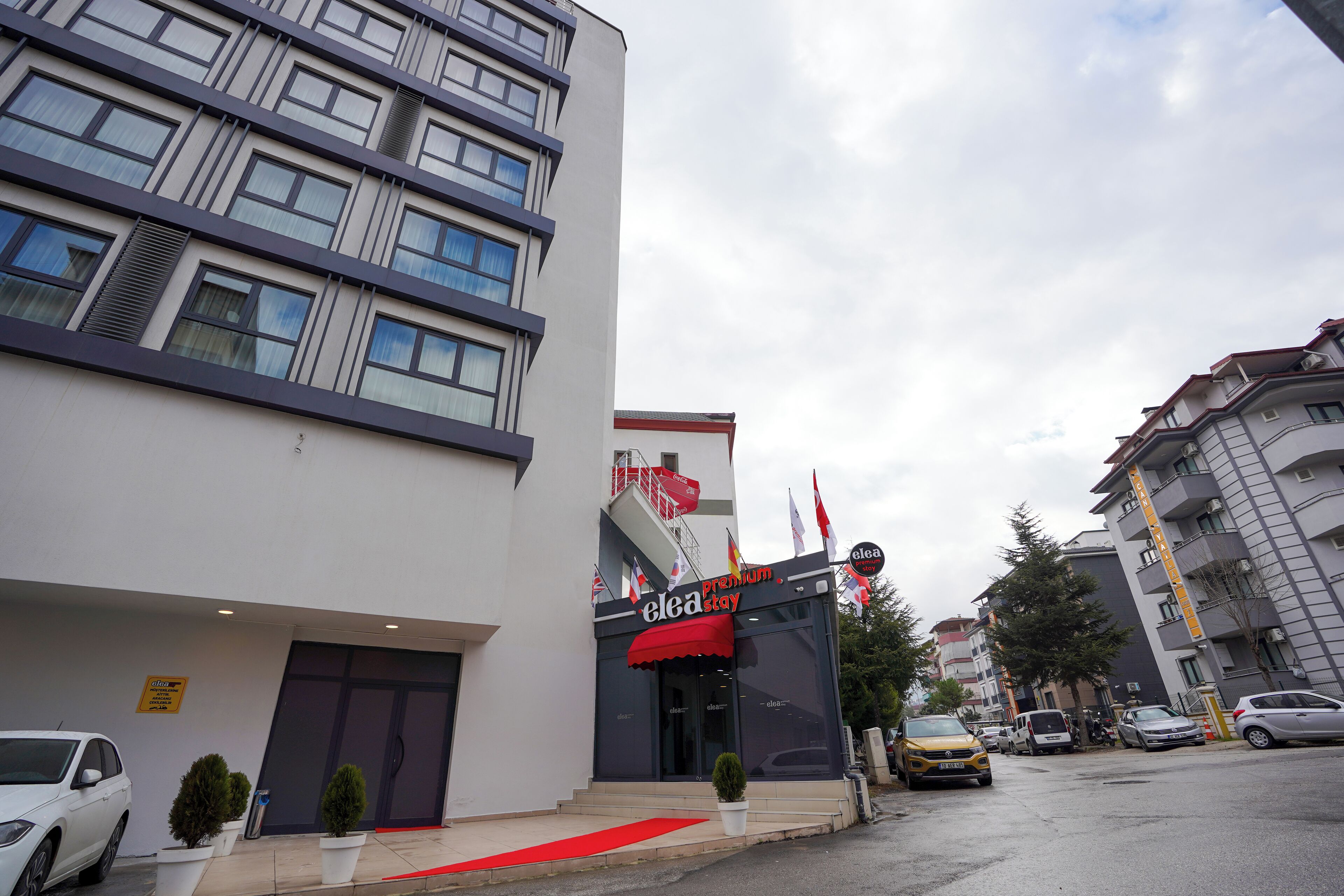 Un hôtel moderne doté d’un auvent rouge, de plusieurs étages et d’un tapis rouge menant à l’entrée.