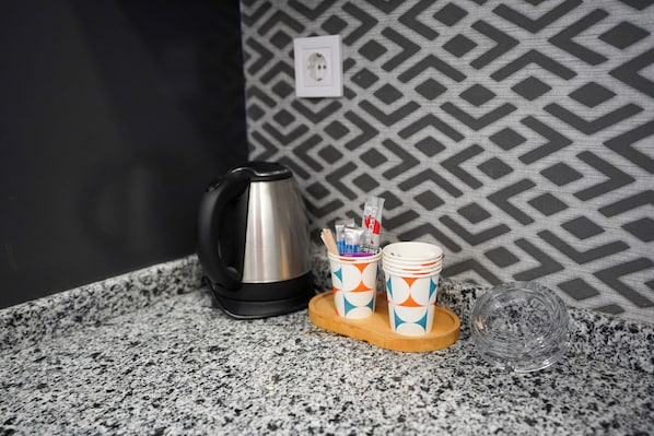 A kitchen counter with a coffee maker, cups, and a glass container. - elea premium stay (Denizli)