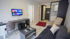 A modern living room with a flat-screen TV, a sofa, a coffee table, and a desk.