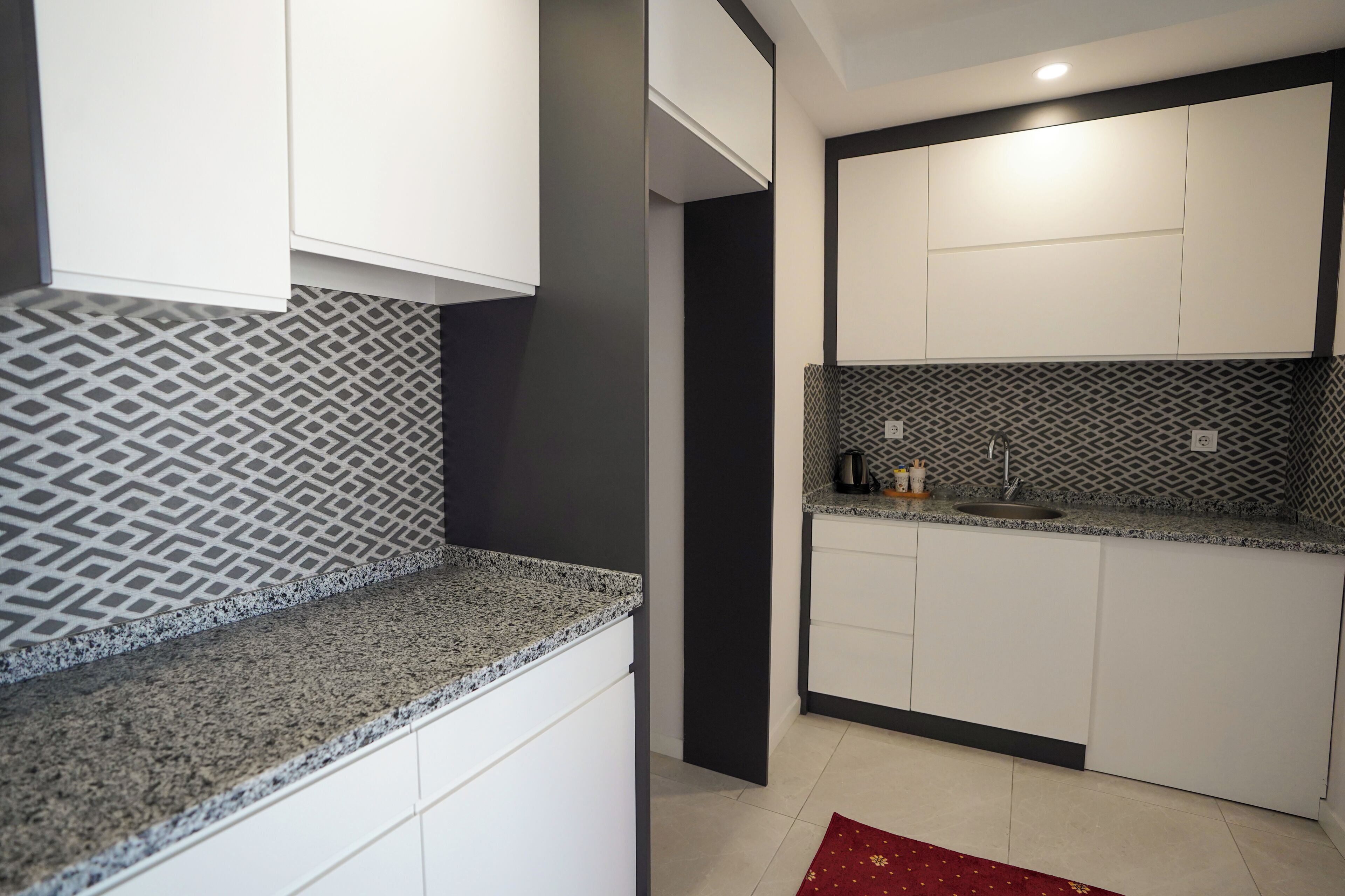 Une cuisine moderne avec des armoires blanches, des comptoirs en granit et un dosseret décoratif.