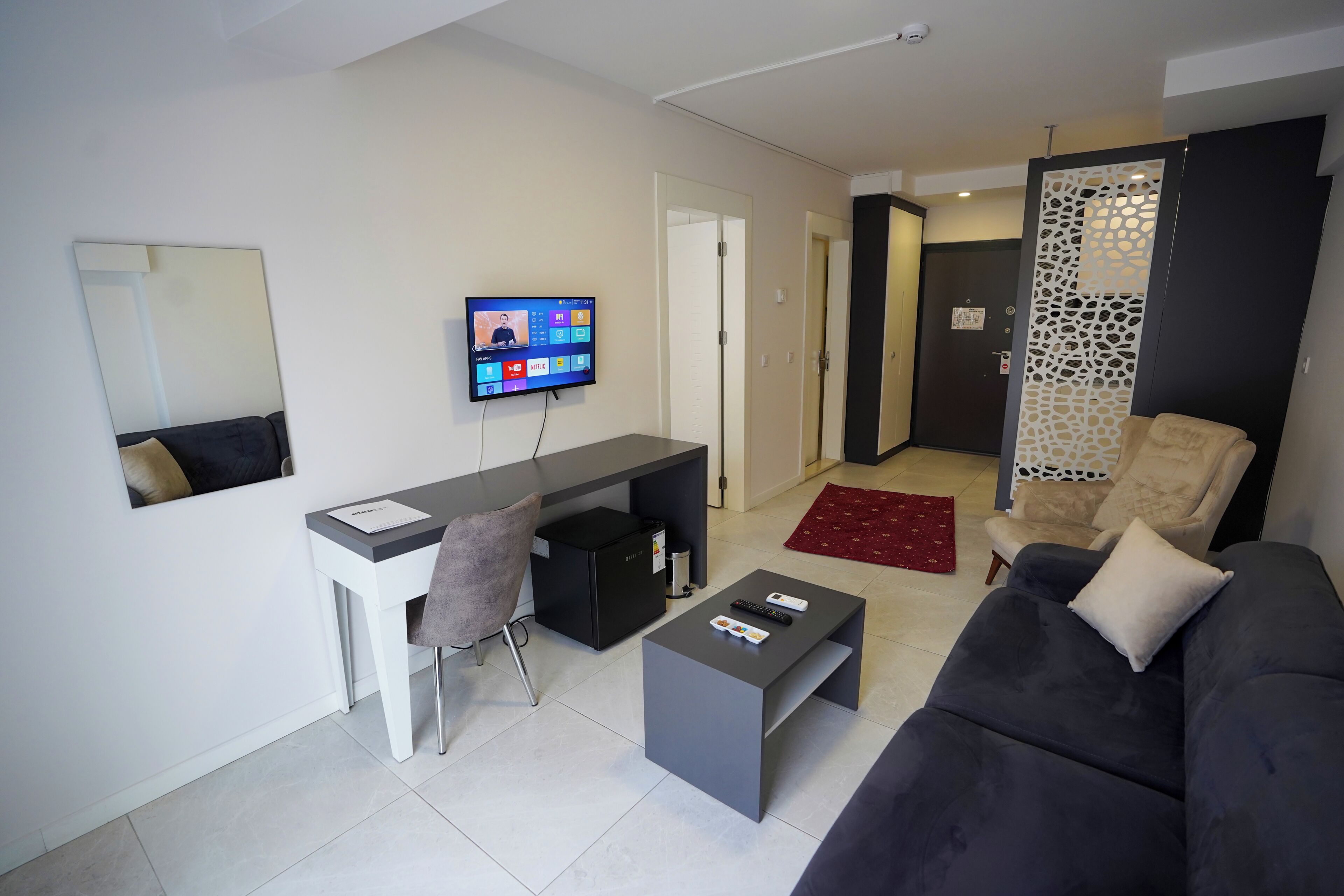 A modern living room with a sofa, a coffee table, a TV, and a desk.
