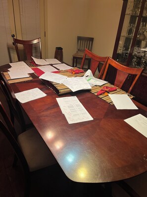 A wooden dining table with papers and a notebook.